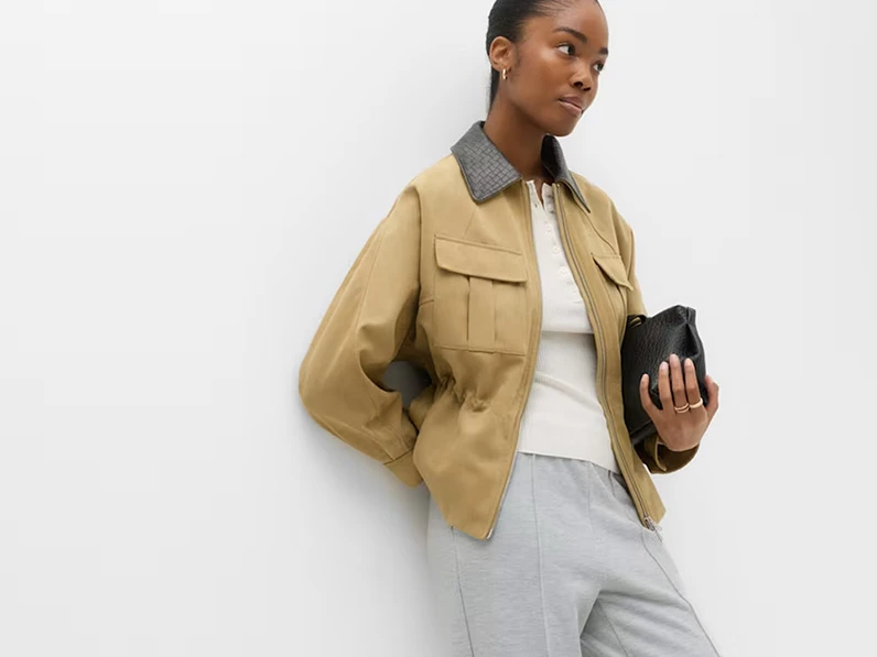 Woman wearing grey joggers and a beige collared coat.