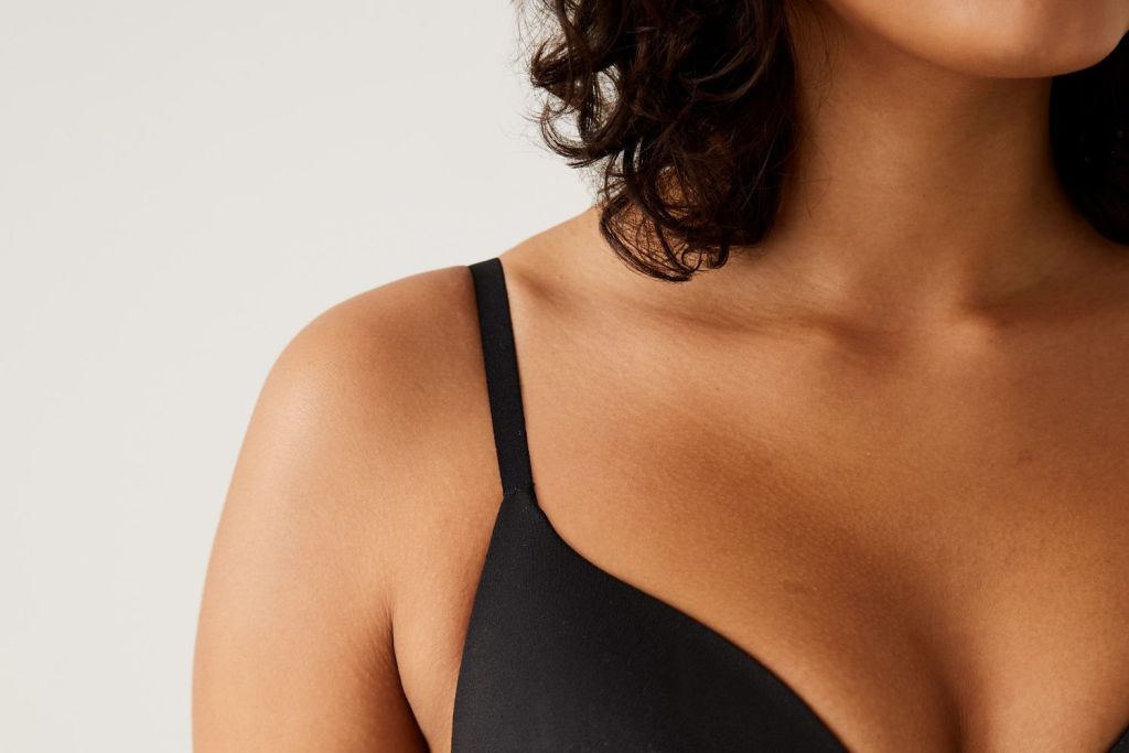 Woman in black bra with straps digging into shoulder. Book a bra fit