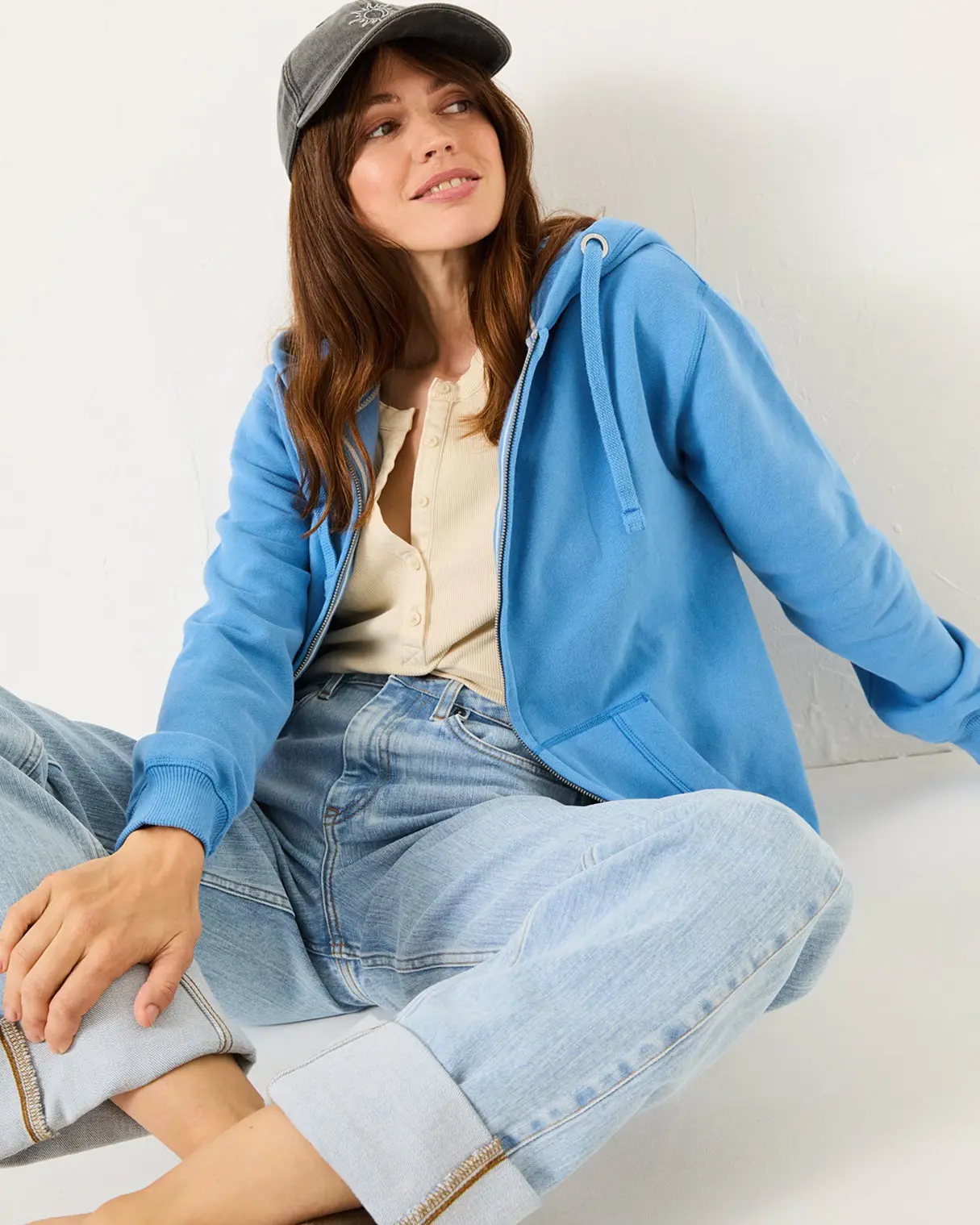 Woman wearing blue hoodie, blue jeans and grey cap