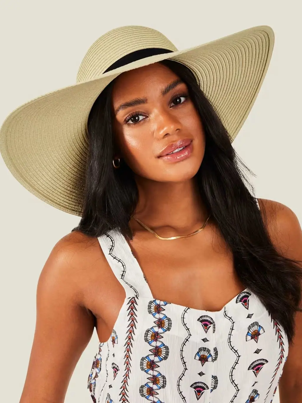 A model wears a wide straw brimmed hat and a dress at a wedding
