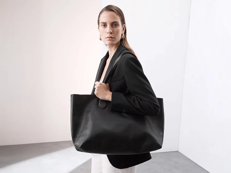 Woman wearing black blazer and carrying a black oversized leather shoulder bag