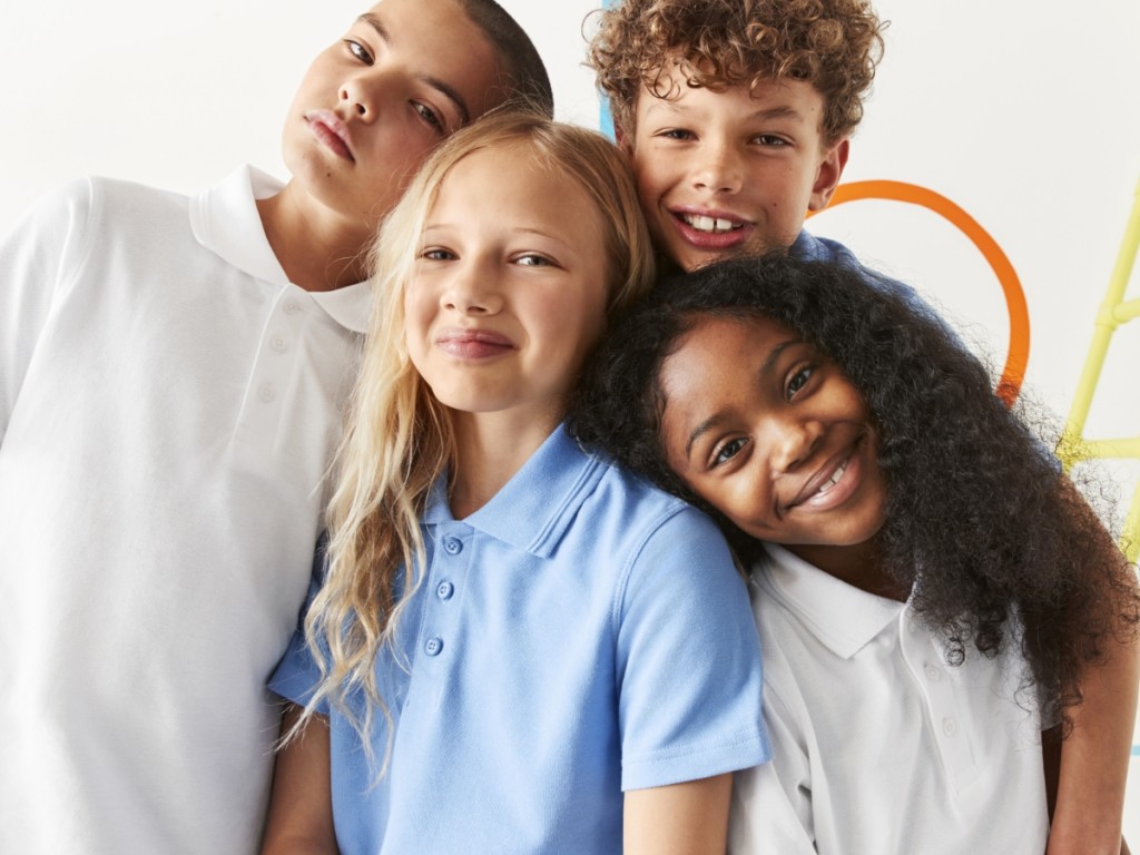 Four children wearing white and blue polo shirts. Shop kids’ school uniform