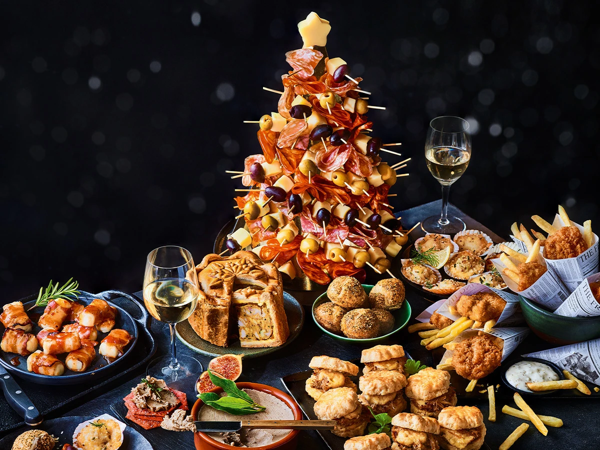 Charcuterie Christmas tree on table with plates of party food