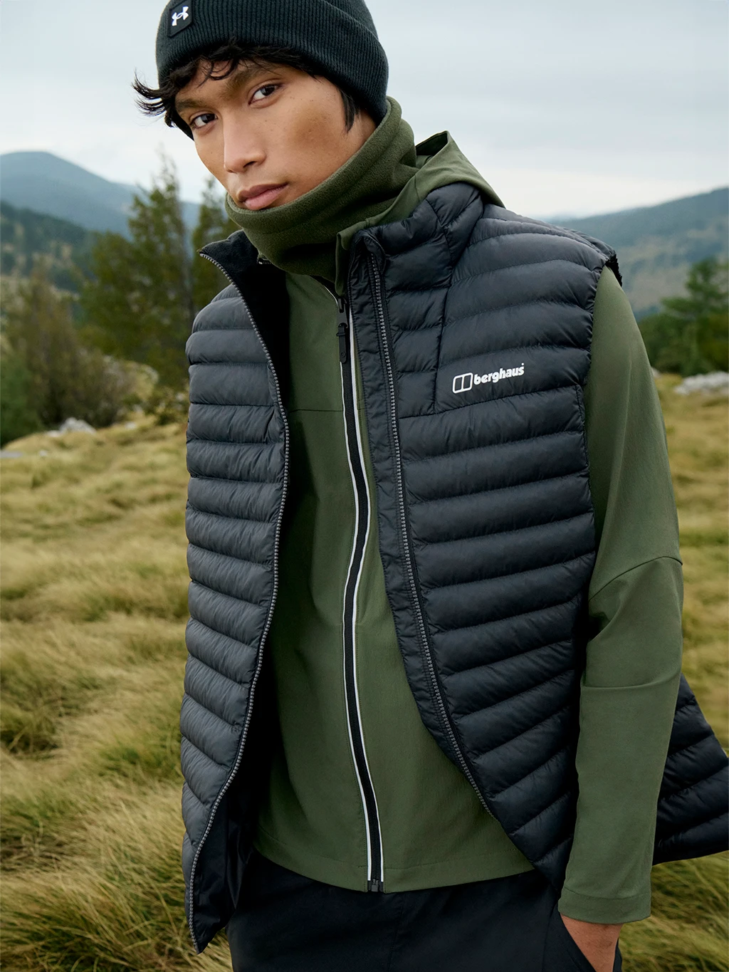Man wearing Berghaus padded gilet, green fleece and black beanie hat