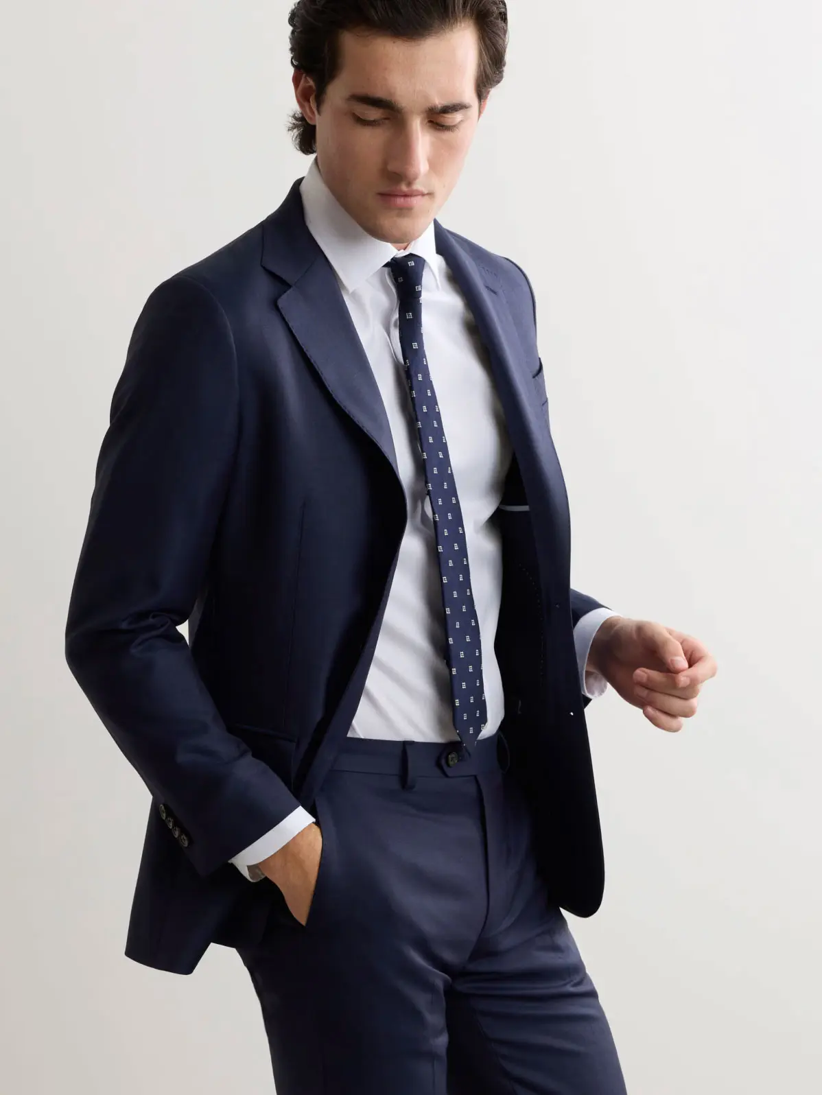 Man wearing navy suit with white shirt and patterned tie