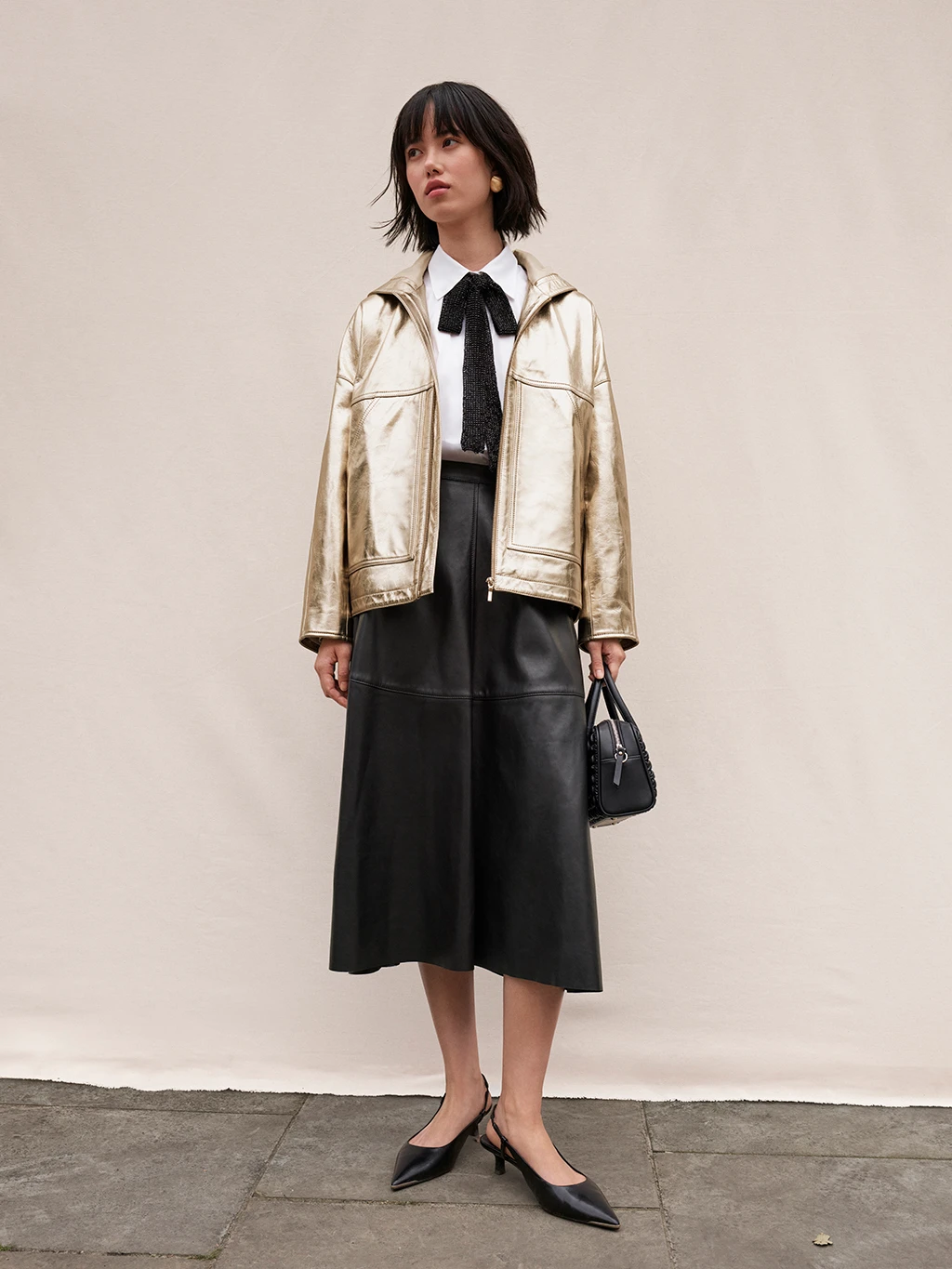 Woman wearing metallic leather jacket and black leather skirt
