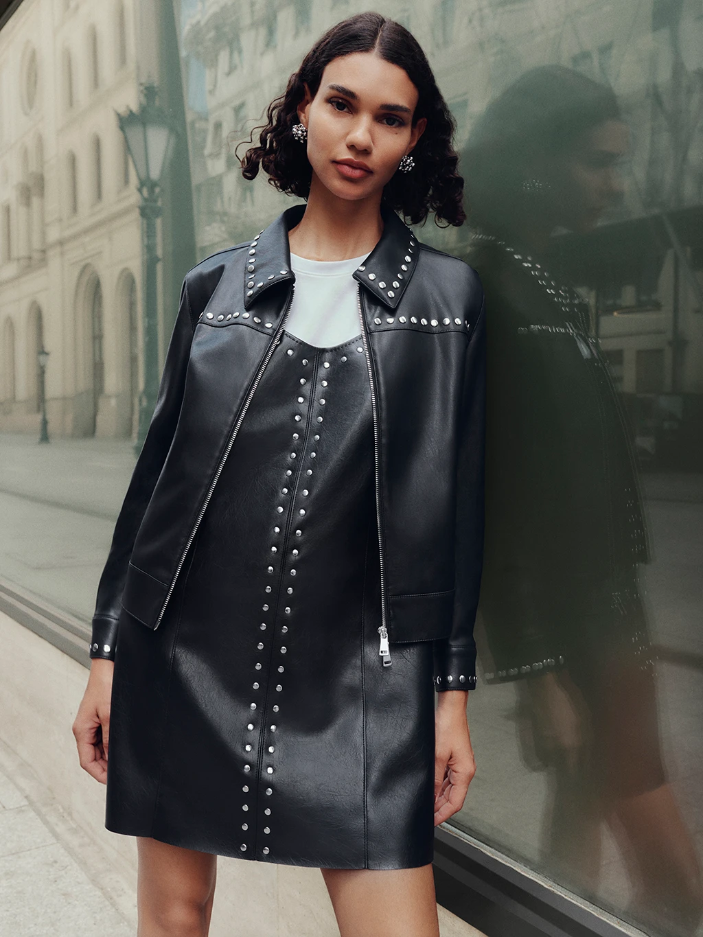 Woman wearing black studded faux leather jacket and black faux leather dress