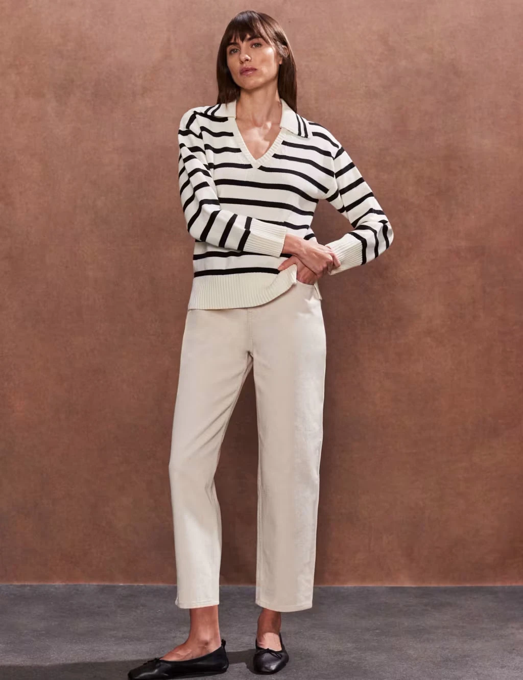 Woman wearing striped jumper and cream trousers with ballet pumps
