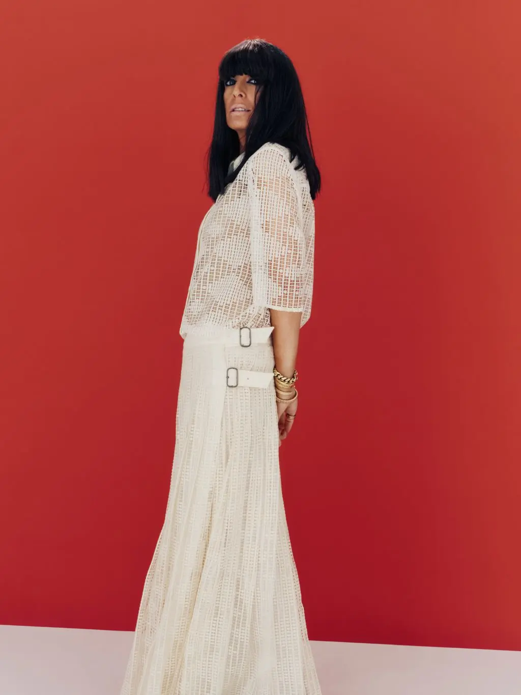 Claudia Winkleman wears an all white outfit - lace shirt and pleated white maxi skirt