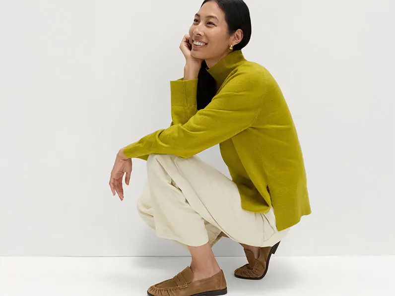 Woman wearing a funnel-neck jumper with cream trousers and loafers