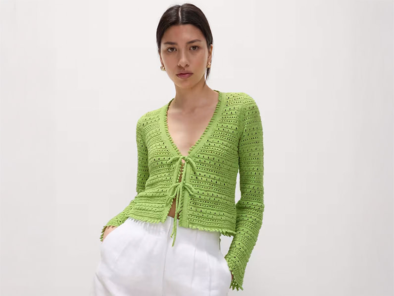 A woman wears a lime-green tie-front top with white linen shorts
