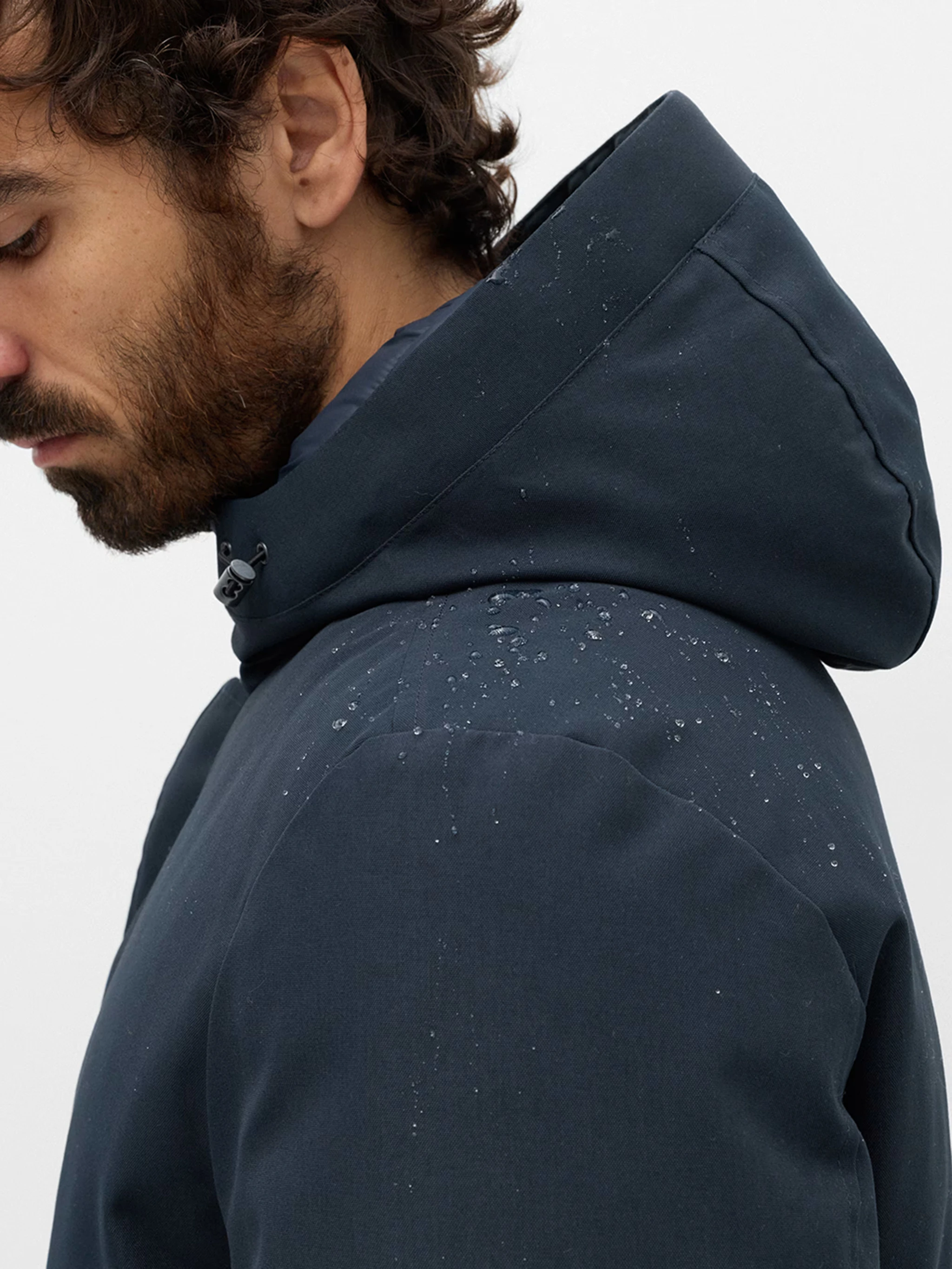 Man wearing a blue parka coat with an adjustable hood.