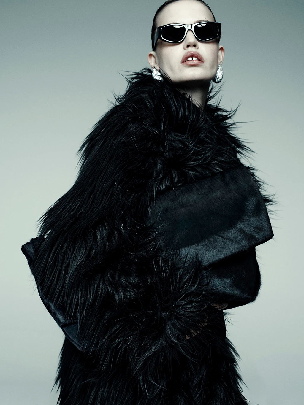Woman wearing black sunglasses and black faux fur coat by M&S x16Arlington