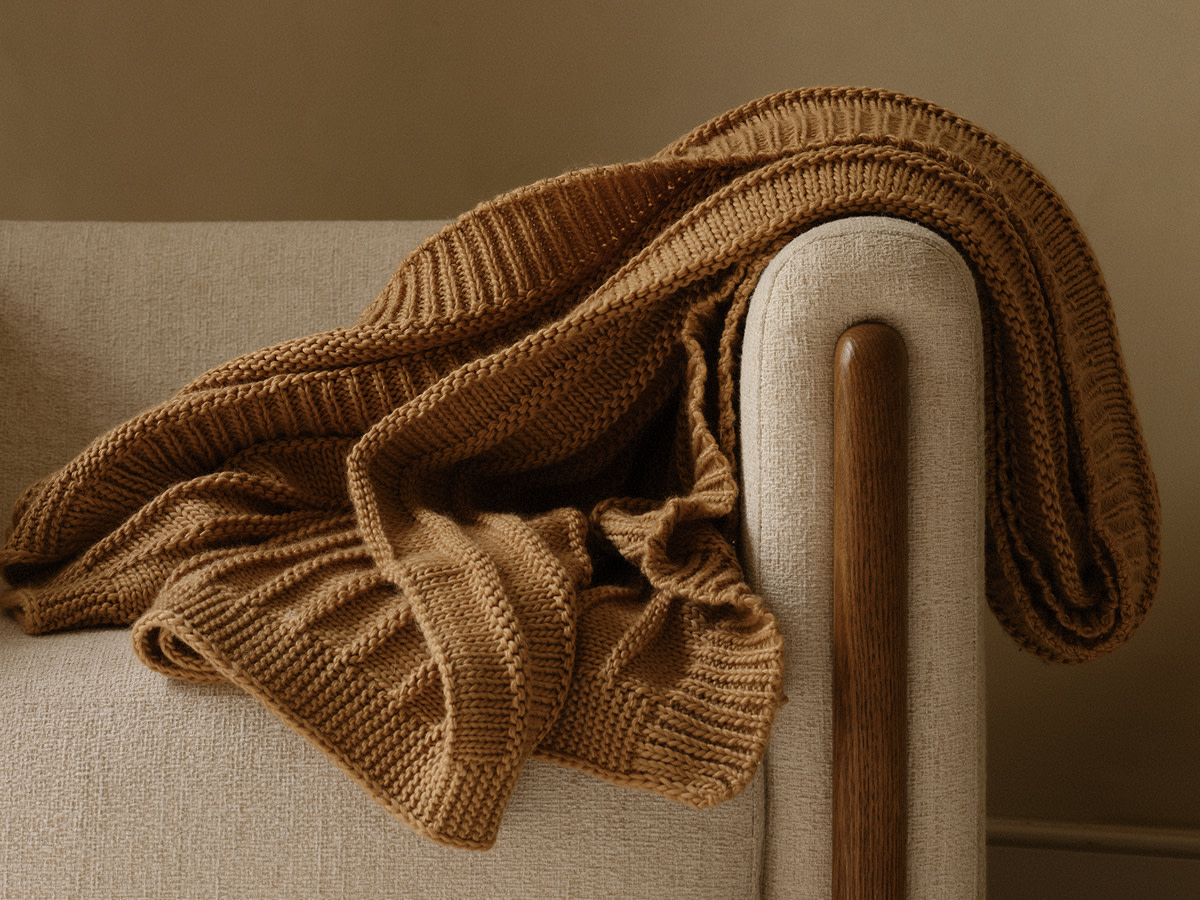 Brown knitted blanket draped over cream sofa 