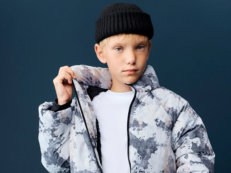 Young child in a white and grey camouflage-print puffer coat. 