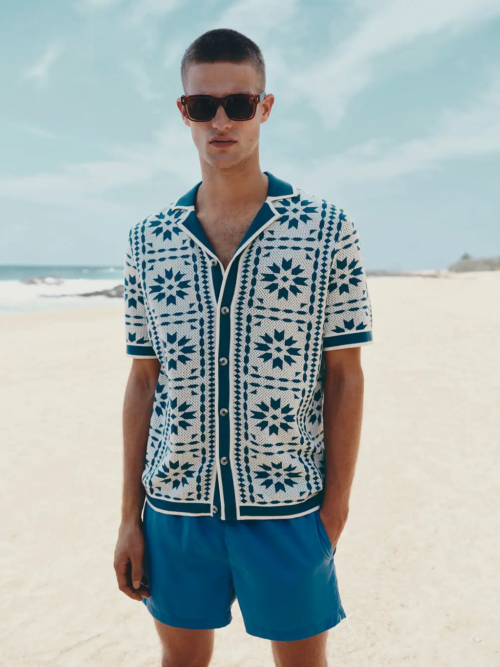 Man in sunglasses and blue shorts on beach 