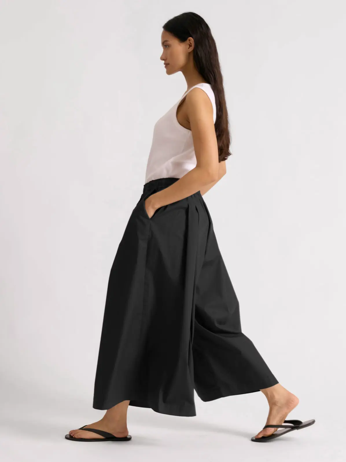 Woman wearing black culottes and white vest top 