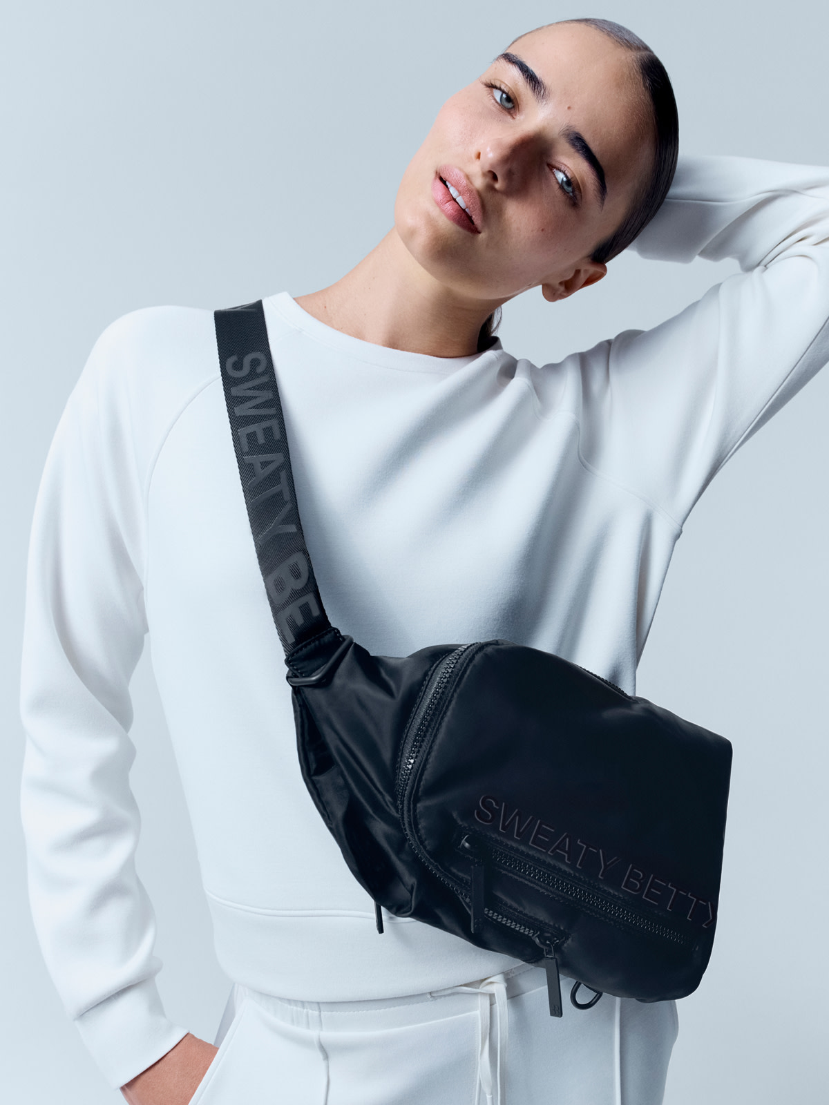 Woman wearing white sweater with a black cross-body bag