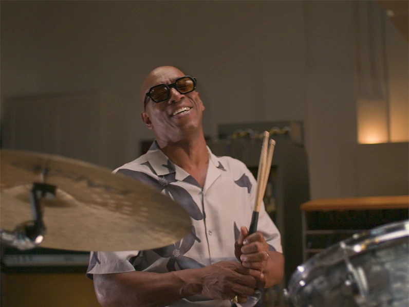 Ian Wright playing the drum kit while wearing M&S clothing