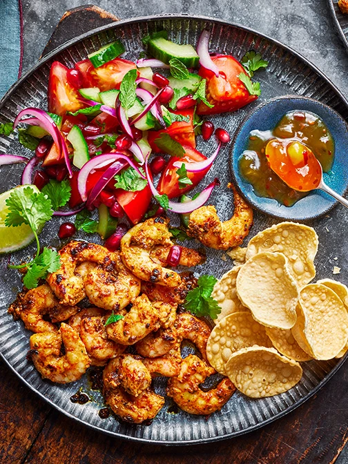 Prawns, salad, poppadoms, and mango chutney on blue plate