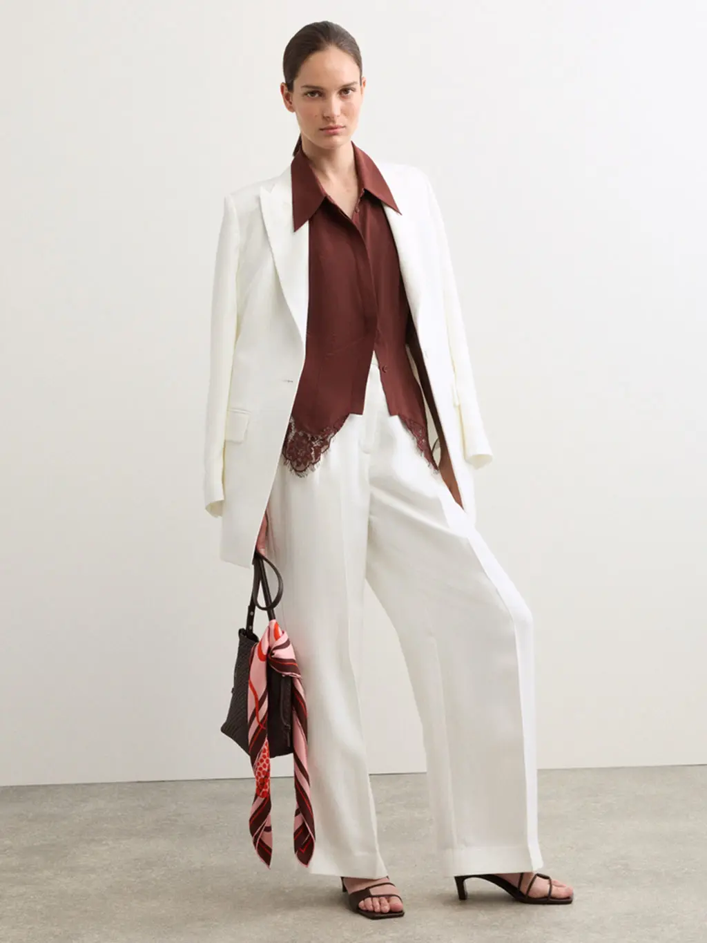 Woman wearing a brown shirt with an ivory basketweave jacket and suit trousers, brown heels and a brown bag