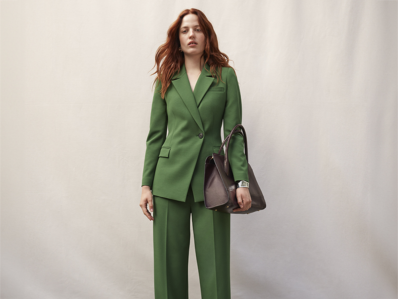 Woman wearing forest green suit and burgundy bag