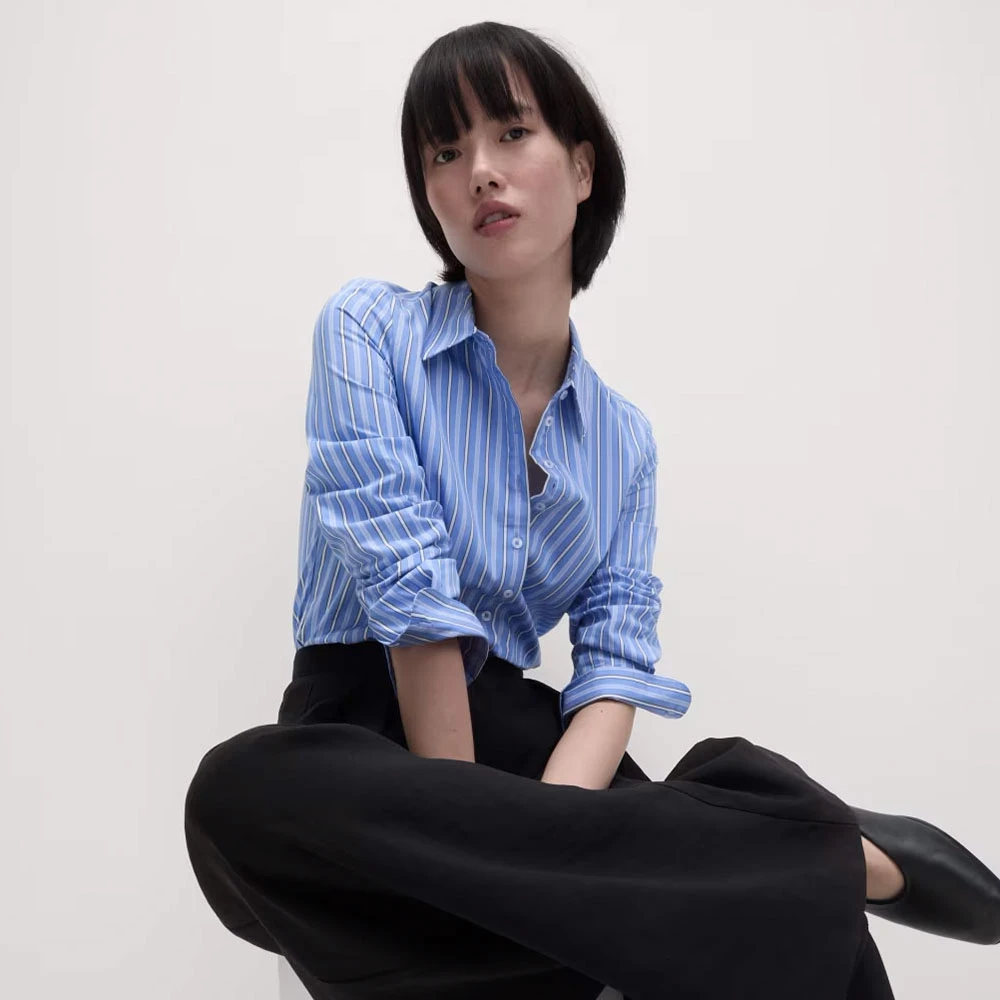 Woman wearing blue striped shirt and black trousers and shoes