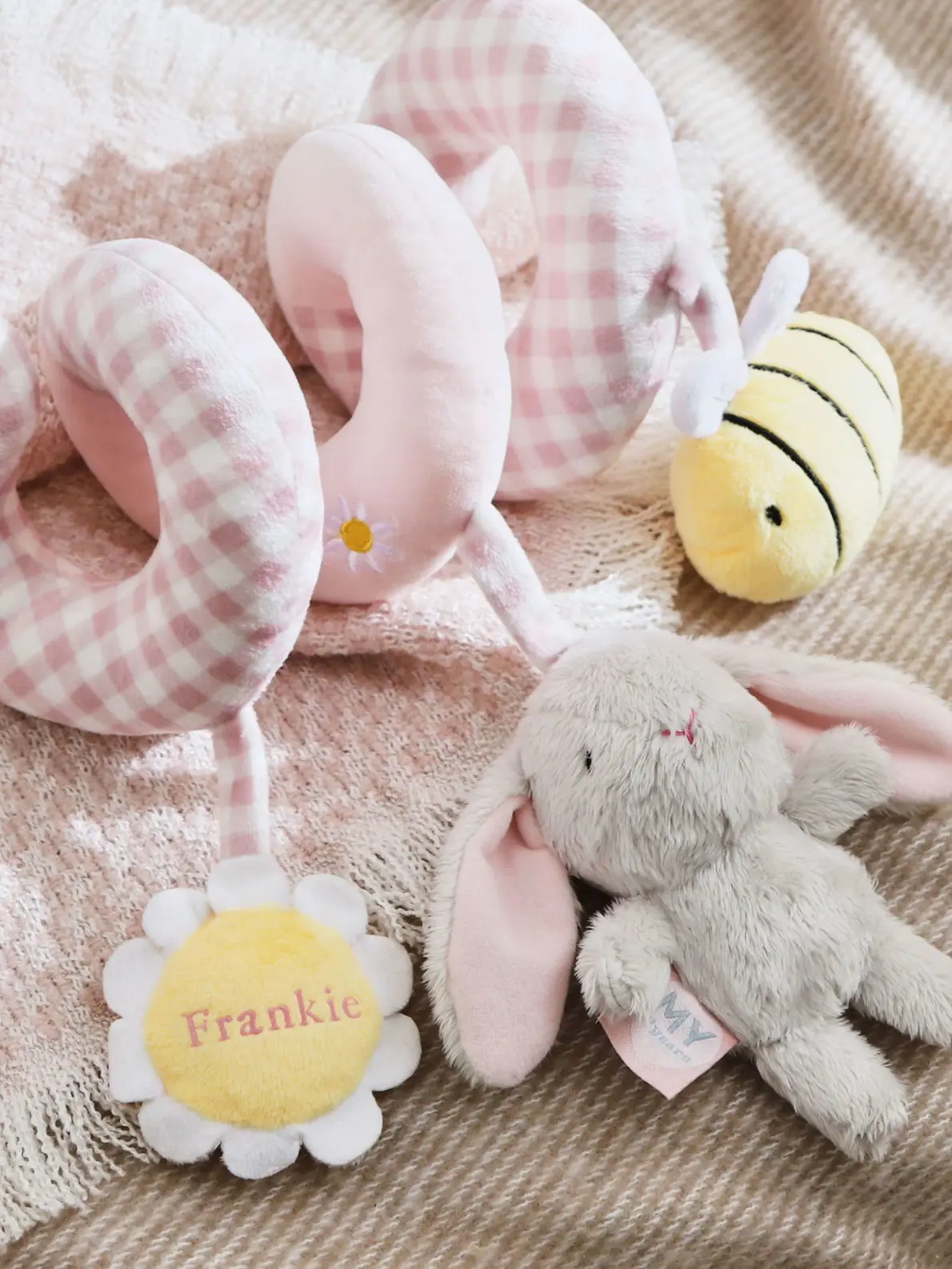 Pink baby toy with 'Frankie' embroidered on a daisy flower, and a yellow and black striped bee and grey bunny toy