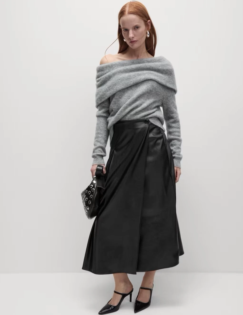 Woman wearing grey off the shoulder jumper and faux leather wrap skirt