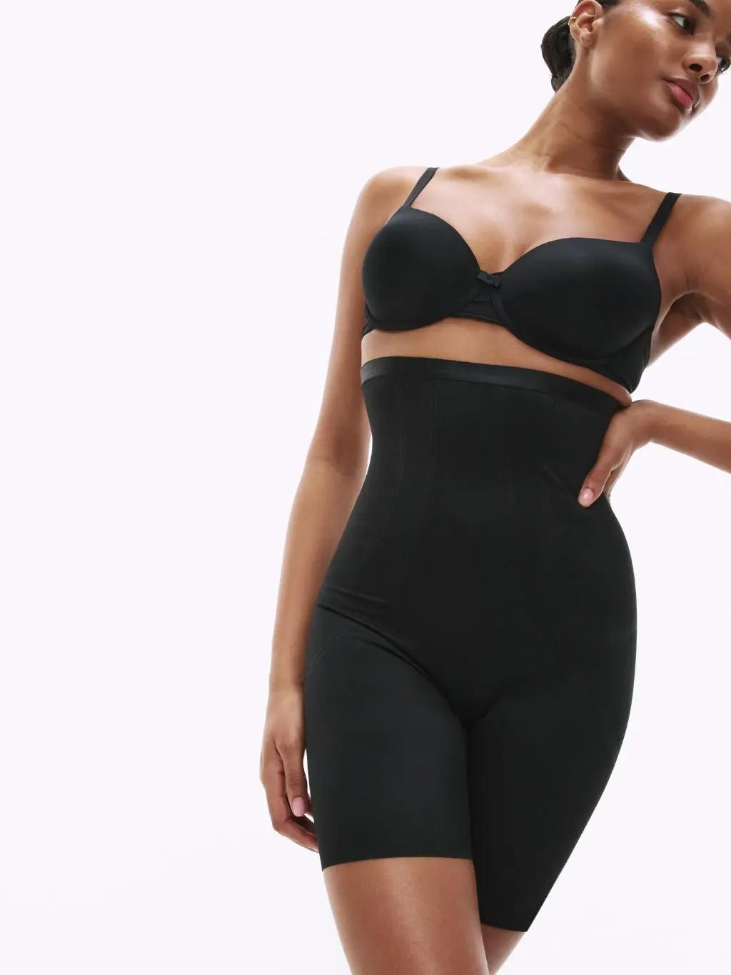 A woman wears a black bra and black Magicwear waist cincher and thigh slimmer by M&S