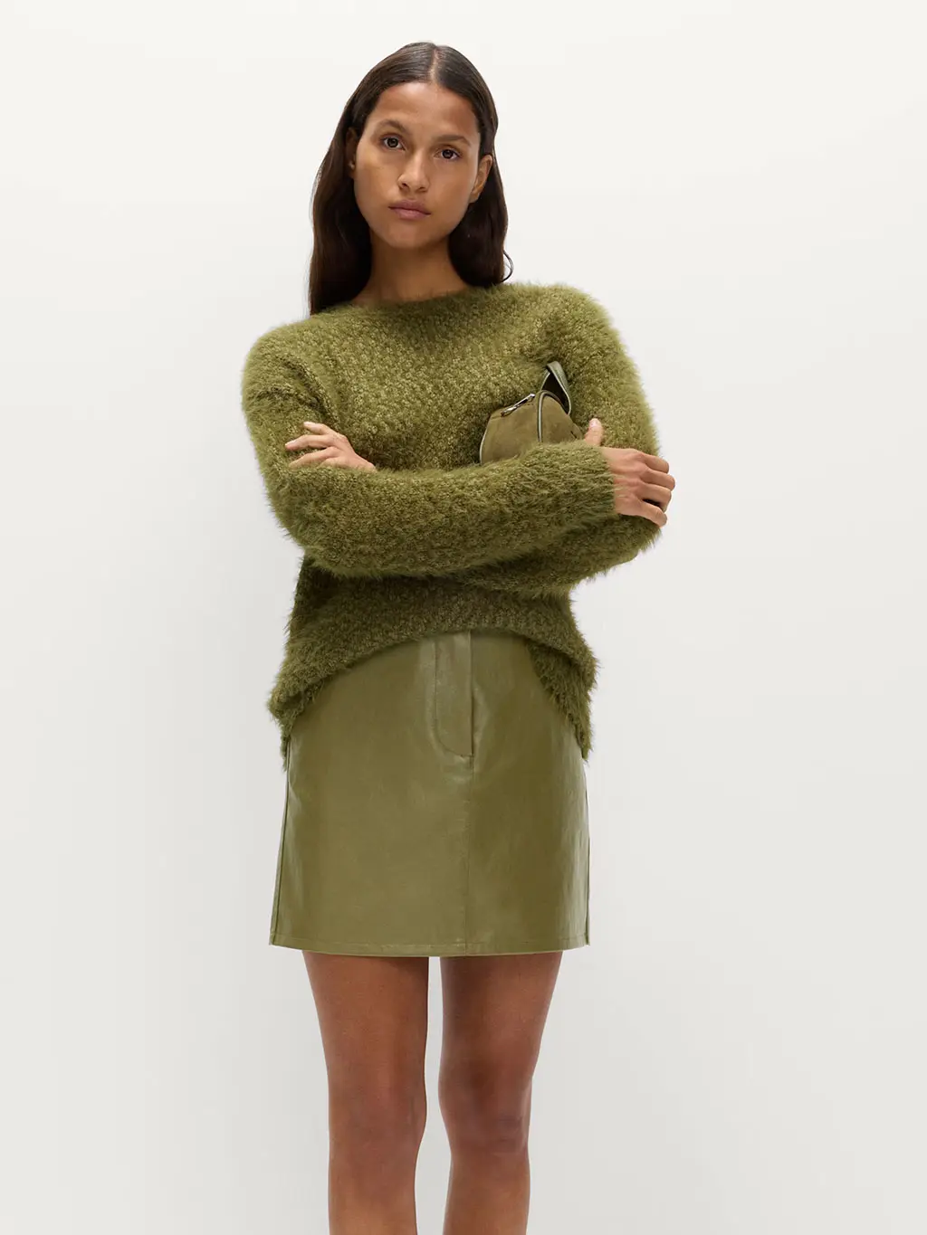 Woman in a green jumper and green mini skirt with a matching bag