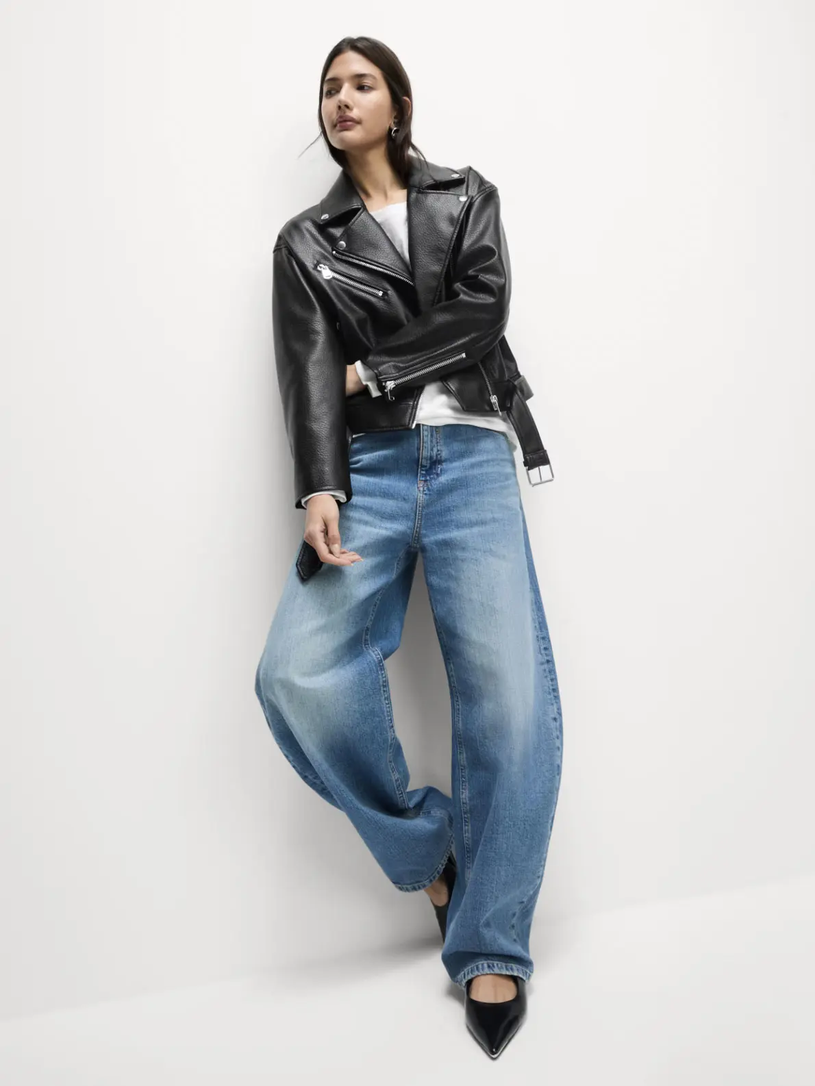 Woman wearing leather jacket over white T-shirt and blue jeans