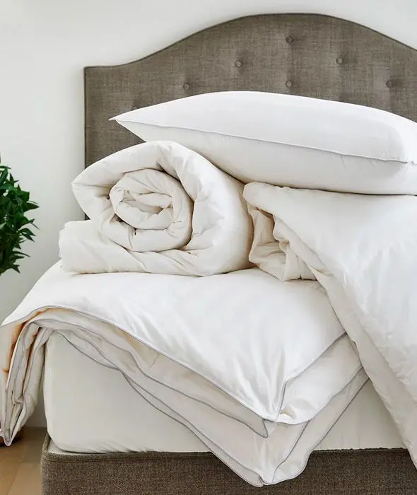 Bed covered in assorted duvets, pillows and mattress toppers