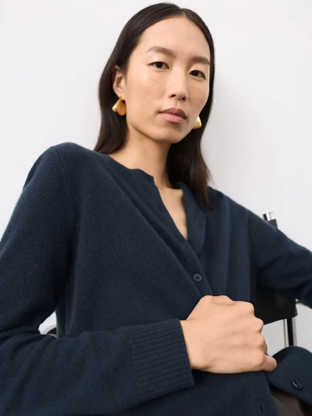 Woman wearing a navy cashmere cardigan with gold jewellery