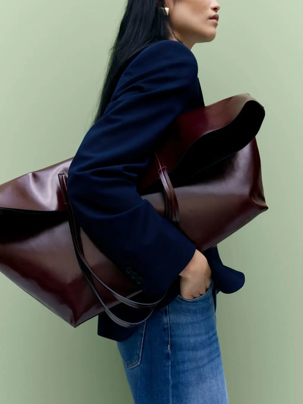 A woman holds a big leather bag under her arm