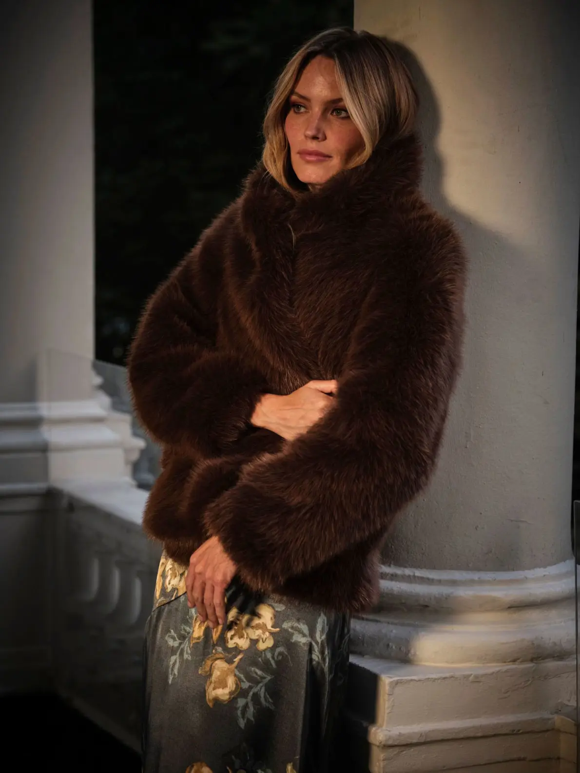 Woman wearing brown short faux fur coat over a floral print dress