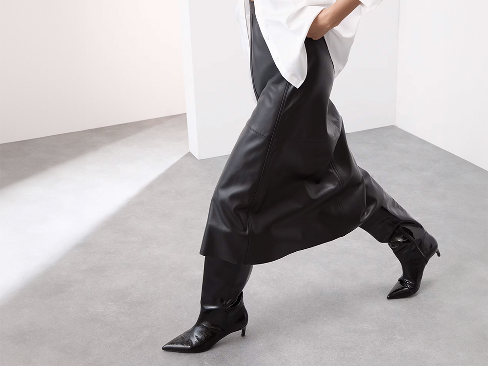 Woman wearing white shirt, black leather midi skirt and black leather knee-high boots