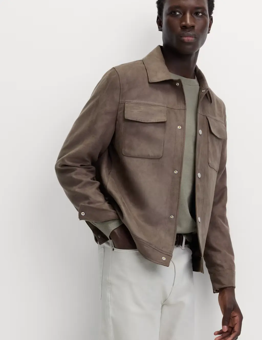 Man wearing a brown faux-suede jacket with cream trousers
