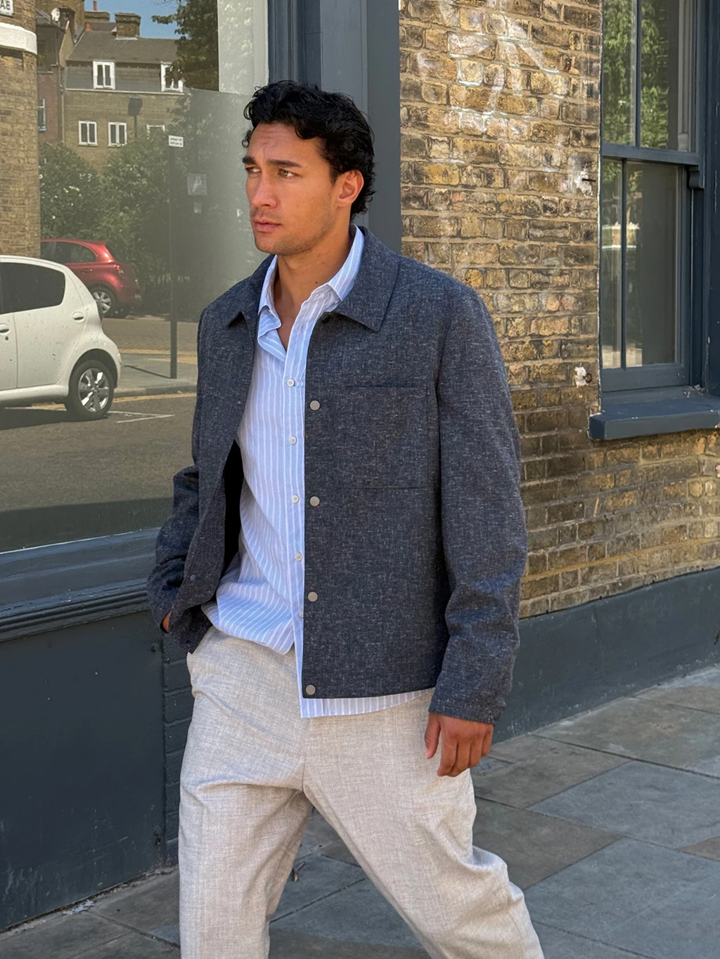 Manawa Owens in navy overshirt, blue shirt, and tan trousers
