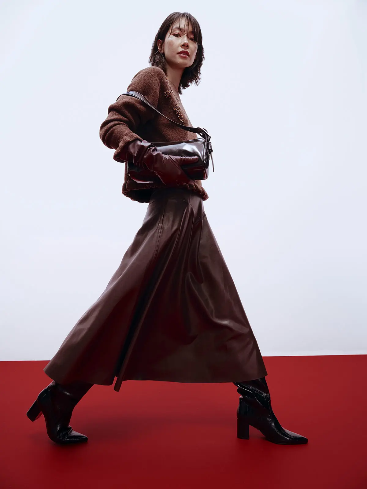 Woman wearing brown jumper, leather gloves, maxi leather skirt and boots