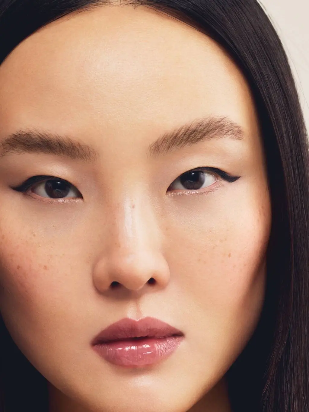 A close up of an Asian woman looking at the camera. She has flicked out eyeliner, natural skin and rosy lips