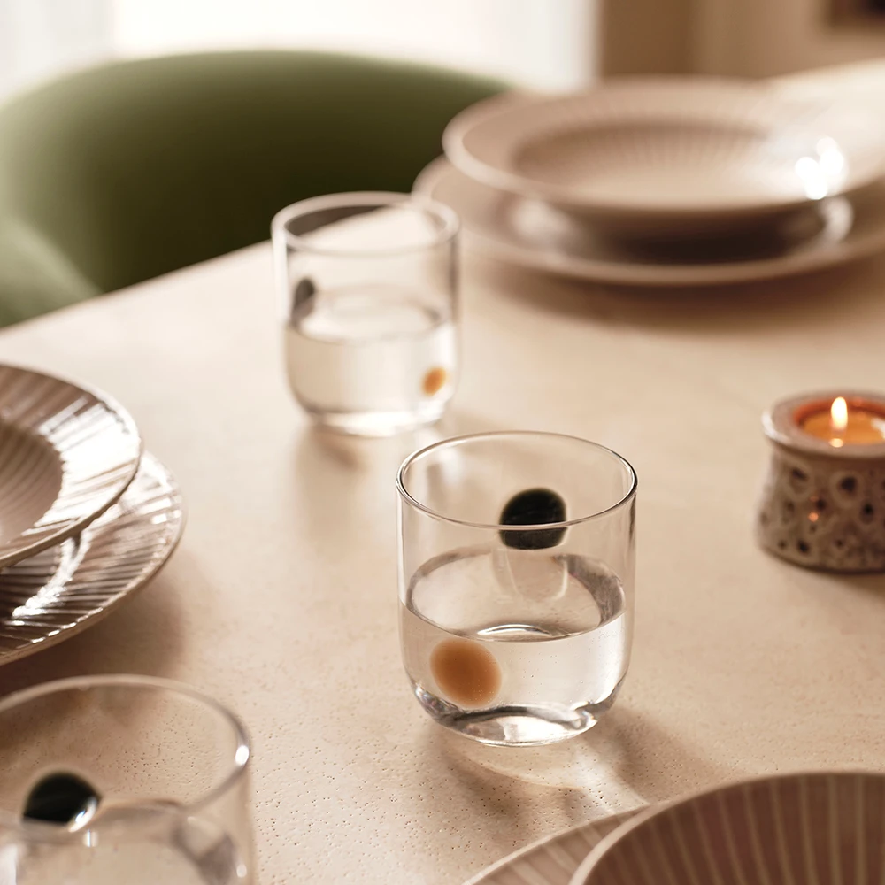 Table set with tablecloth, spotted glasses, tea lights and ceramic dishes