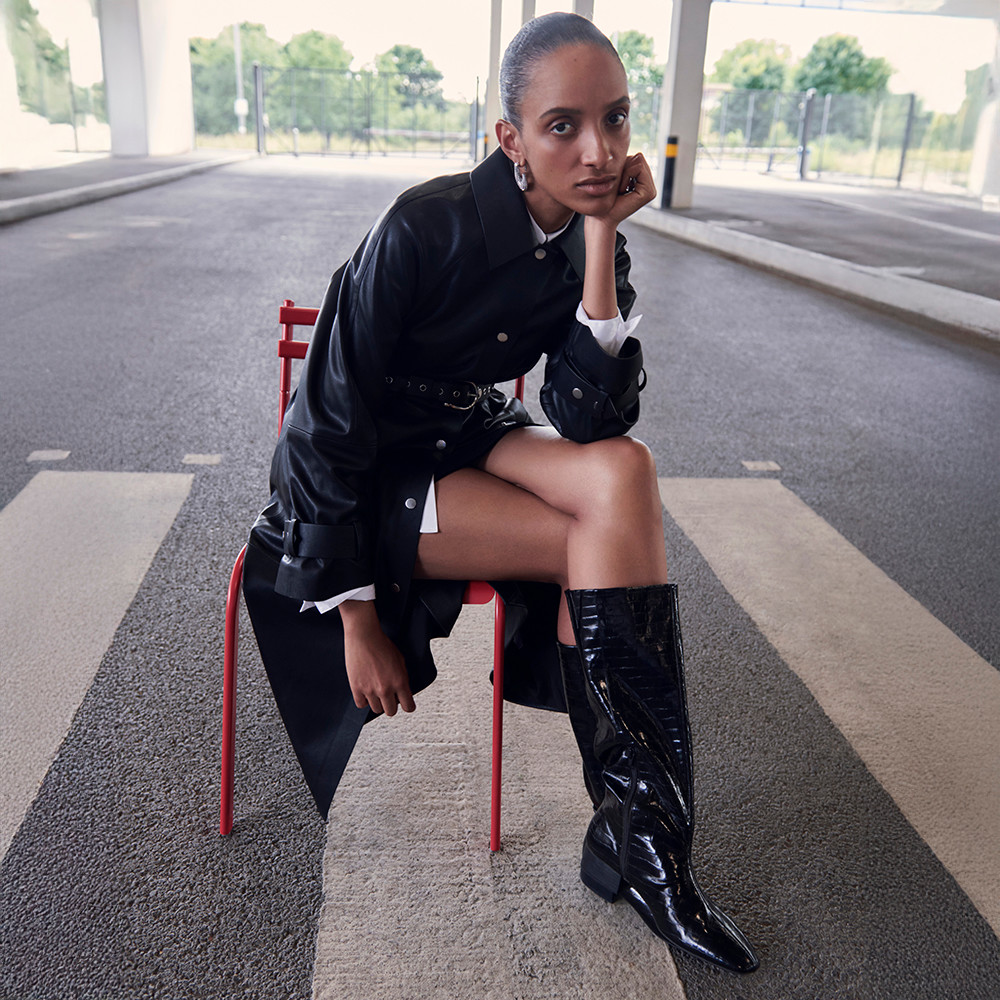 Woman wearing black belted jacket and knee-high boots