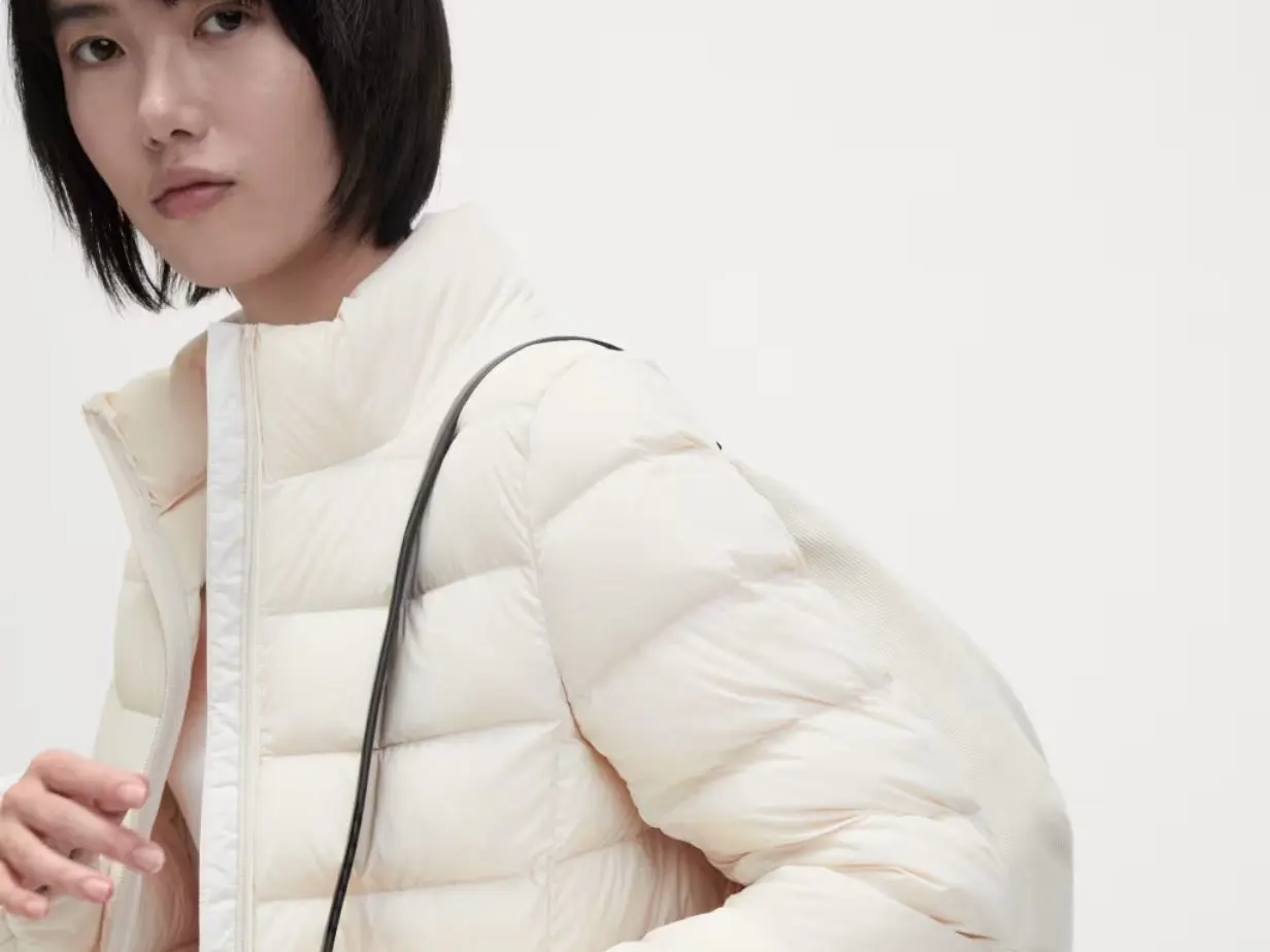 A woman wearing a white puffer jacket with a bag over her shoulder