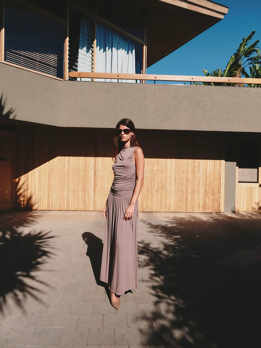 Woman wearing a brown gathered dress, sunglasses and heels
