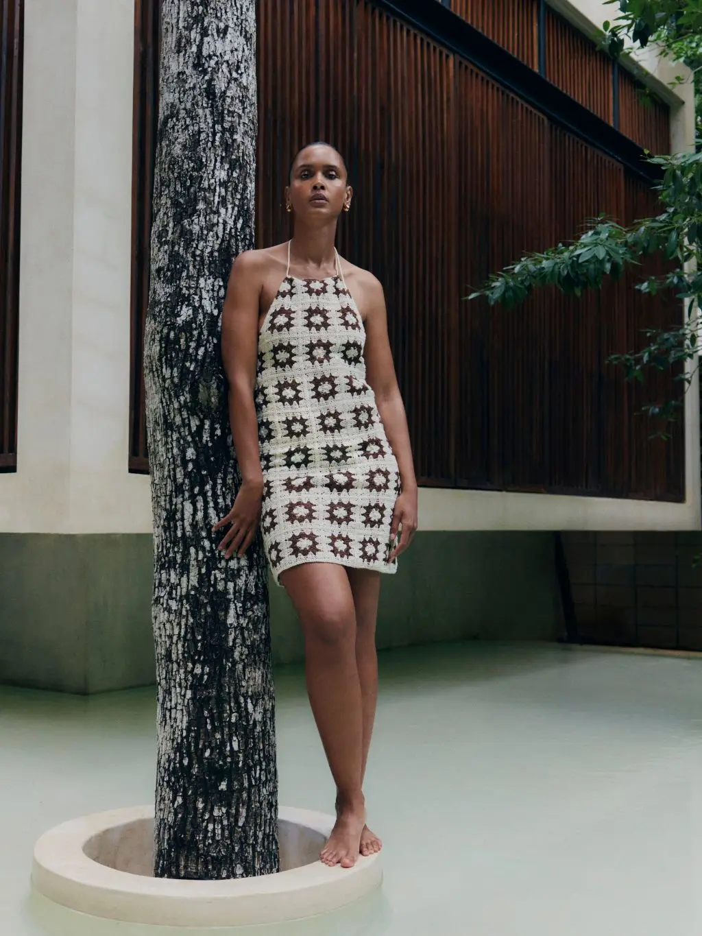 A woman wears a cream and brown crochet halterneck dress