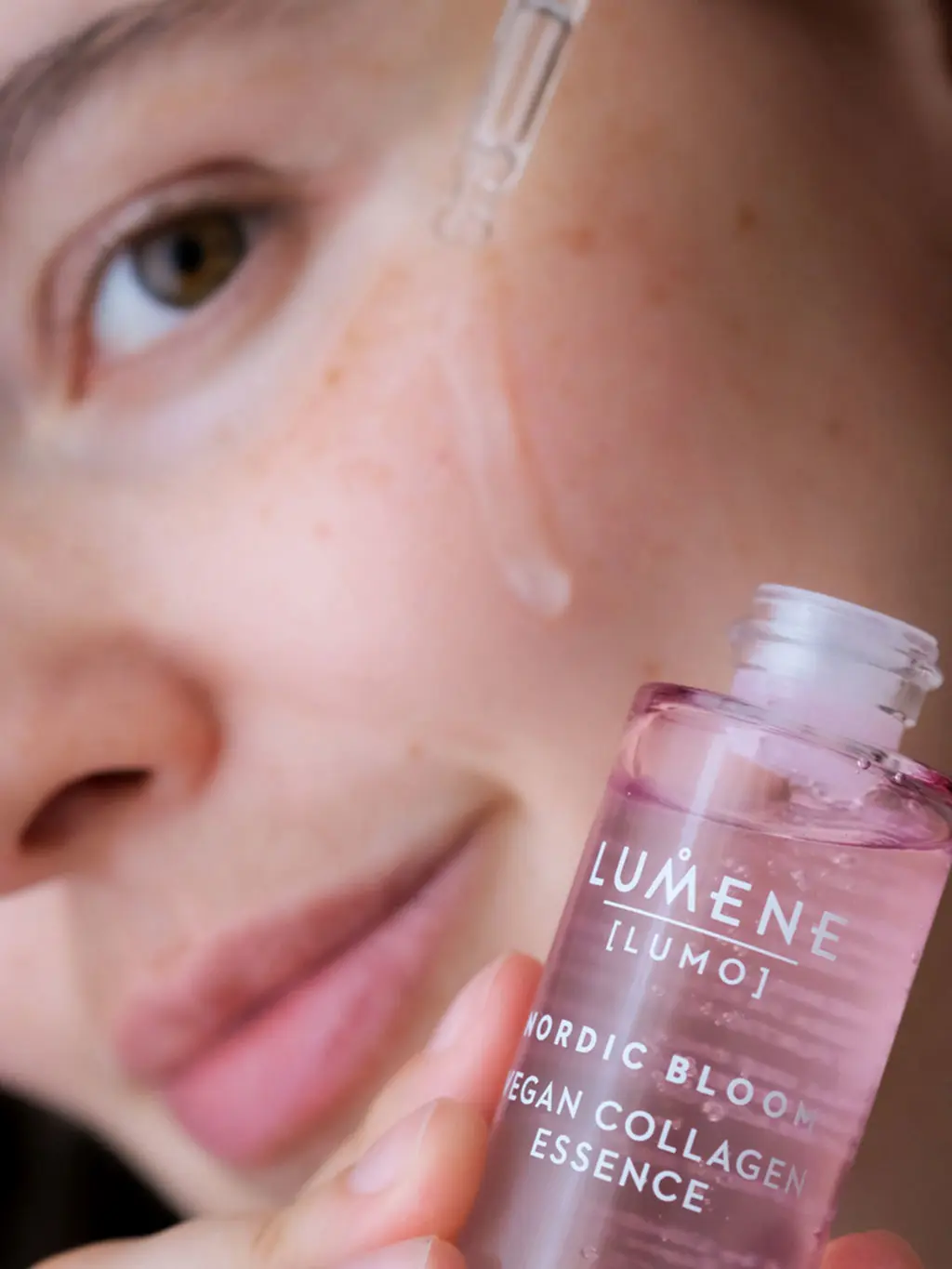 Woman holding a bottle of collagen serum against her cheek