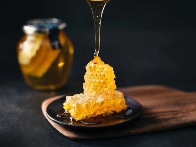 Honey being drizzled onto black plate