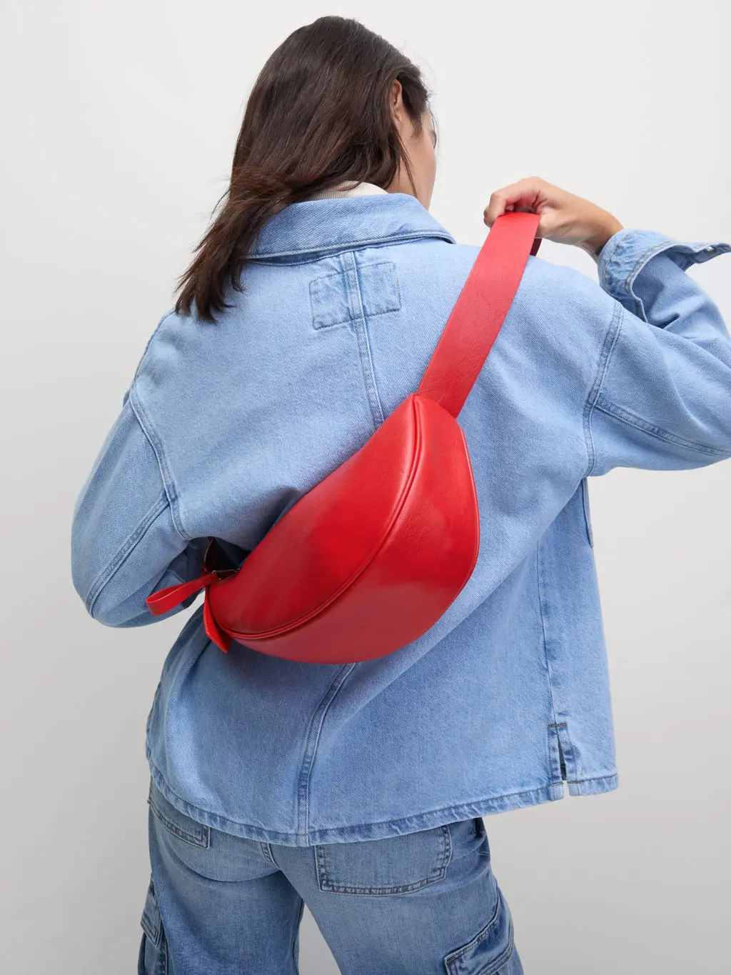 Woman in denim shirt and jeans wearing red cross-body bag