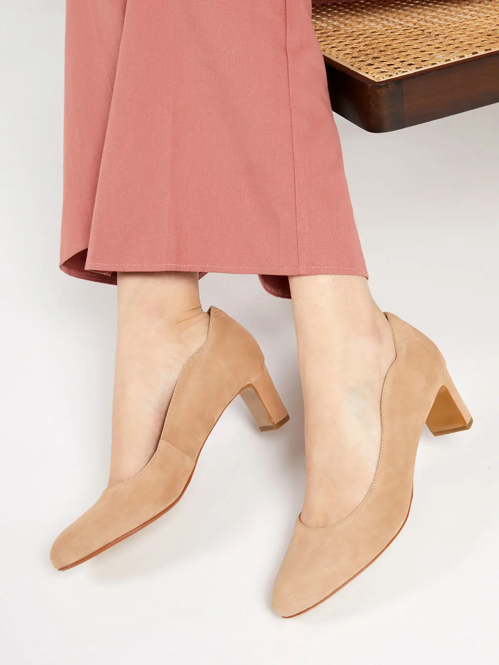 Woman wearing a pair of beige mid heel shoes with pink trousers